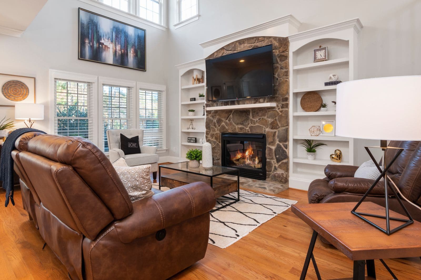Large TV mounted cleanly over a stone fireplace in a bright Utah living room